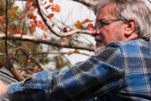 Vinson Home Inspections (1) older man working on a roof, holding a hammer in his right hand