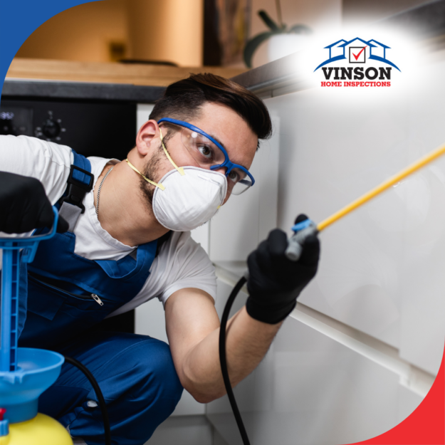Vinson Home Inspections (16) Pest control technician wearing protective gear spraying pesticide in a kitchen.