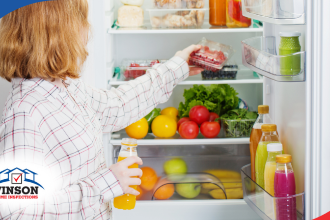 Vinson Home Inspections Woman placing berries in a refrigerator stocked with fruits, vegetables, and drinks.